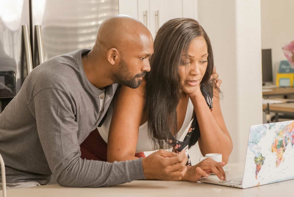 Couple using the computer to read about why we don't take insurance for couples therapy
