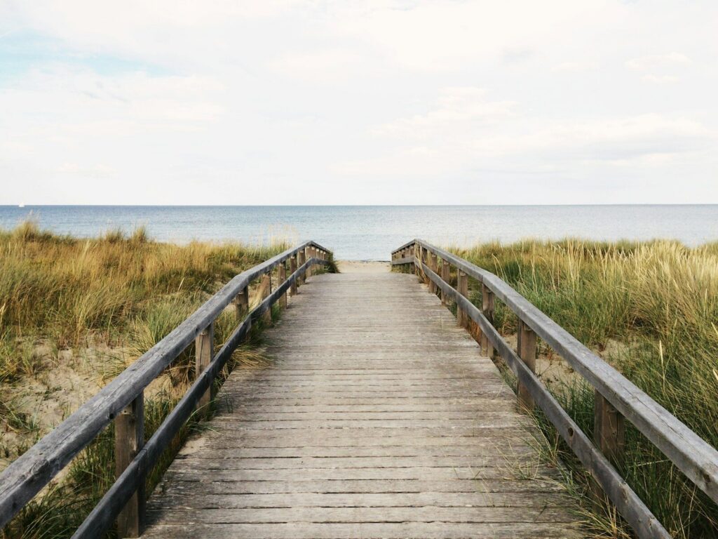 photo of gray wooden bridge towards water relaxing