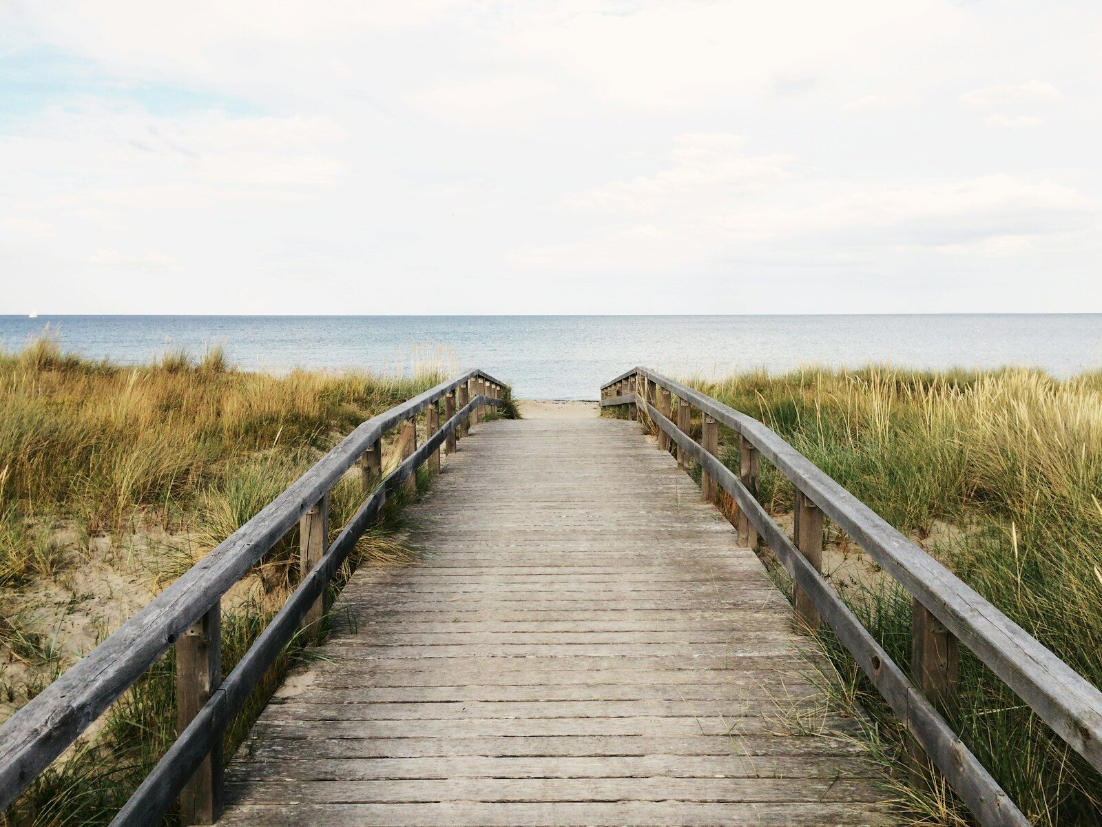photo of gray wooden bridge towards water relaxing